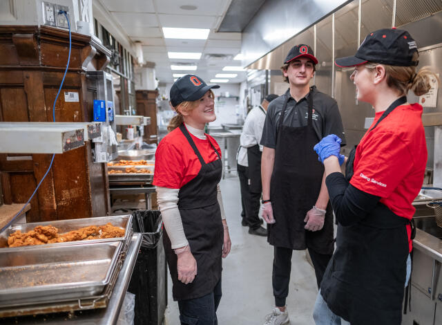 Three students engaging in conversation in a kitchen